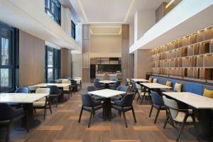 a dining room with tables and chairs and windows at Fairfield by Marriott Changchun Chaoyang in Changchun
