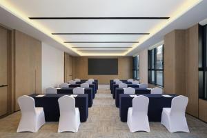 a conference room with tables and chairs and a screen at Fairfield by Marriott Changchun Chaoyang in Changchun