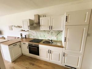 a white kitchen with white cabinets and a sink at Seestern Strobl in Strobl