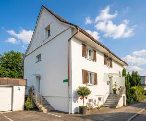 a white house with stairs and a porch at Chalet zum See in Bregenz