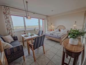 a living room with a bed and a table at FeWo Sonnenschein mit Pool & Balkon in Horumersiel