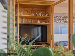 a tv in a wooden cabinet with a television at FeWo Sonnenschein mit Pool & Balkon in Horumersiel