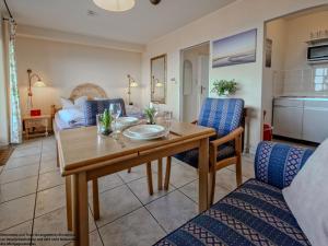 a living room with a wooden table and chairs at FeWo Sonnenschein mit Pool & Balkon in Horumersiel