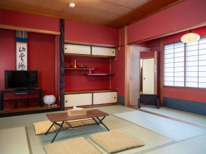 a living room with red walls and a table at Guesthouse Nagonde in Kanazawa
