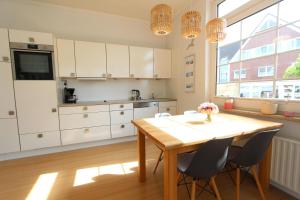 a kitchen with white cabinets and a wooden table and chairs at Langeoog entspannt in Langeoog