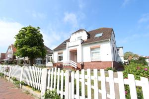 a white picket fence in front of a house at Langeoog entspannt in Langeoog