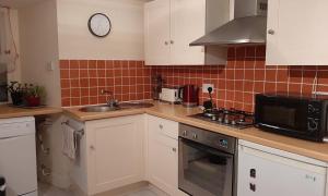 a kitchen with white cabinets and a sink and a microwave at Beulah Serviced bedrooms in Aberdeen +10 photos