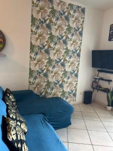 a blue couch in a room with a wall at LE MERYCE appt in Saint-Denis