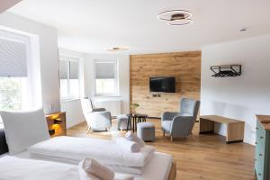 a living room with a bed and chairs and a tv at Alfredo Hotel in Eppingen