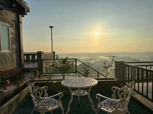 a table and chairs on a balcony with a view at Tsuya Hill Private Mountain View Villa, Chiang Rai in Mae Chan