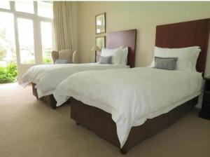a hotel room with two beds with white sheets at J&J Paradise Guesthouse in Pietermaritzburg +6 photos