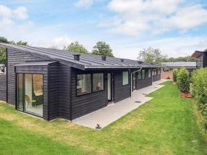 a house with black siding and a green yard at Kysthusene in Gilleleje