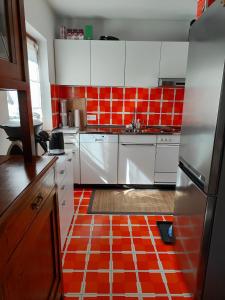 a kitchen with white cabinets and red tiles on the floor at Casa Laetitia in Acquarossa