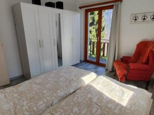 a bedroom with a bed and a chair and a window at Casa Laetitia in Acquarossa
