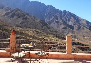 a table and chairs on a balcony with a mountain at gite ogog tachedirt in Tacheddirt