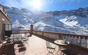 a balcony with tables and chairs and a snow covered mountain at gite ogog tachedirt in Tacheddirt
