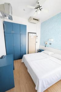 a bedroom with a white bed and a blue wall at Dipendenza Hotel Regal in Rimini
