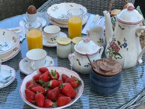 a table with a plate of strawberries and cups of juice at Chez Lapage in Saint-Avit-Sénieur +23 photos