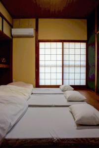 a group of four beds in a room with windows at ゲストハウス青い輝き in Marugame