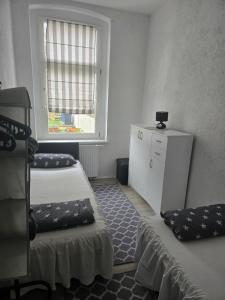 a small room with two beds and a window at Ferienwohnung 1 am Bahnhof in Bernburg