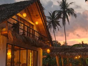 a building with palm trees in the background at Lahima Cabanas Villa in Dickwella