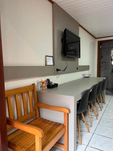 a room with a bar with chairs and a television at Suite Familia A1 in Pomerode