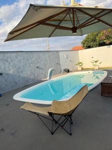 a swimming pool with an umbrella and a chair at Casa de piscina Pôr do Sol in Chapadão do Sul