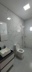 a white bathroom with a toilet and a sink at Casa de piscina Pôr do Sol in Chapadão do Sul