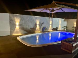 a large swimming pool with an umbrella in a room at Casa de piscina Pôr do Sol in Chapadão do Sul