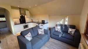 a living room with two blue couches and a kitchen at Bunroy Park in Fort William