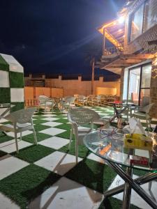 a patio with tables and chairs on a checkered floor at Taj Plaza in Sowayma