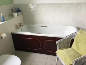 a bath tub in a bathroom with a chair at Woodcockfaulds House in Stirling +54 photos