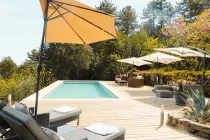 a swimming pool with a yellow umbrella and chairs at Idyllic Roulotte in Les Assions