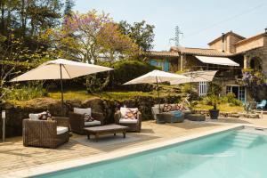 a pool with chairs and umbrellas next to a house at Idyllic Roulotte in Les Assions