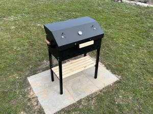a bbq grill sitting on the grass at Greencabin - Cabin Escape in the Heart of Saaremaa in Pamma