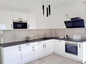 a kitchen with white cabinets and a black counter top at Penthouse Vue Panoramique in Mechernich +3 photos