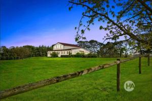a house on a green field with a fence at Peninsula Farm Stay in Somerville