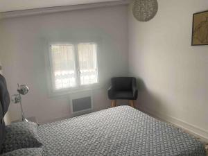a bedroom with a bed and a chair in it at T2 cyclamen independent in Cholet