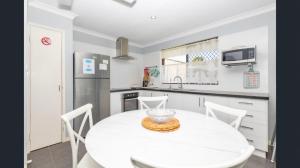 a white kitchen with a white table and chairs at Ocean Beach Chalet 18 in Jurien Bay