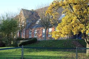 una casa de ladrillo con un árbol delante de ella en Ferienhof Harrsen, en Pellworm