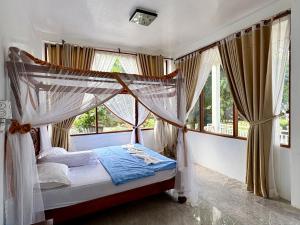 a bedroom with a canopy bed in front of windows at JungleRiverHouse & JungleRiverResort in Bukit Lawang
