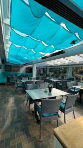 a restaurant with tables and chairs and a blue ceiling at Feriensiedlung Schwalbennest - Bungalows in Dranske