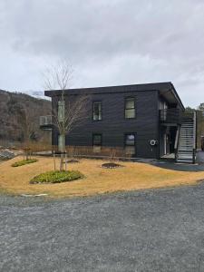a black house with a tree in front of it at Hardanger Granvin Living in Granvin