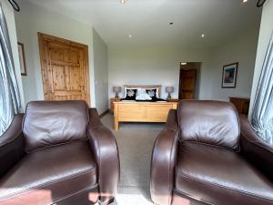 a living room with two leather chairs and a bed at Dingle Mist in Dingle