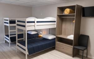 a bunk bed room with two bunk beds and a chair at Hôtel Le Petit Logis Chambres Confort climatisées in Beaumont-en-Véron
