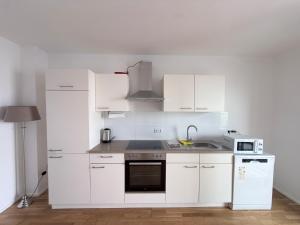 a white kitchen with white cabinets and a sink at LuxApart2Cologne in Kerpen +40 photos