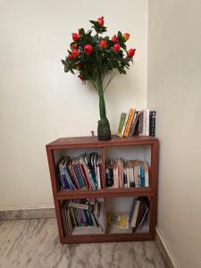 a vase with red flowers sitting on a book shelf at Monkey Temple Homestay in Kathmandu