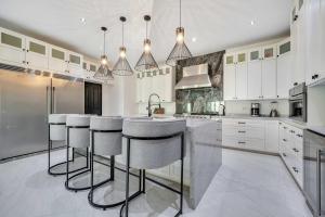 a kitchen with white cabinets and bar stools at Marbella Lane Coastal Elegance Villa with Pool in Cabo San Lucas