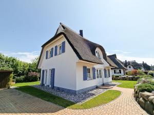 a white house with a black roof and a driveway at Ferienhaus Dwarslöper mit Sauna und Garten in Fuhlendorf in Fuhlendorf