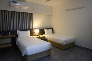 a hotel room with two beds and a table with a lamp at Pearl Serenity in Sholāshahar +66 photos